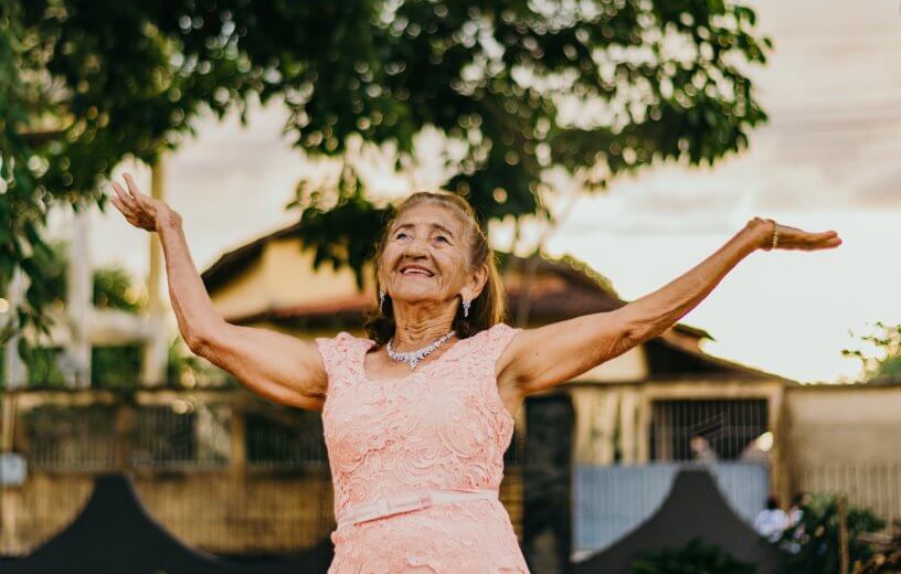 Long, happy life: Elderly woman with hands in the air