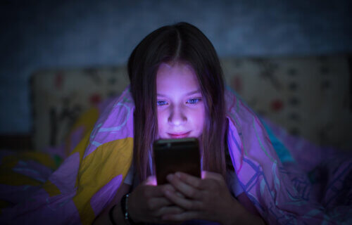 Teen girl in bed looking at smartphone at night