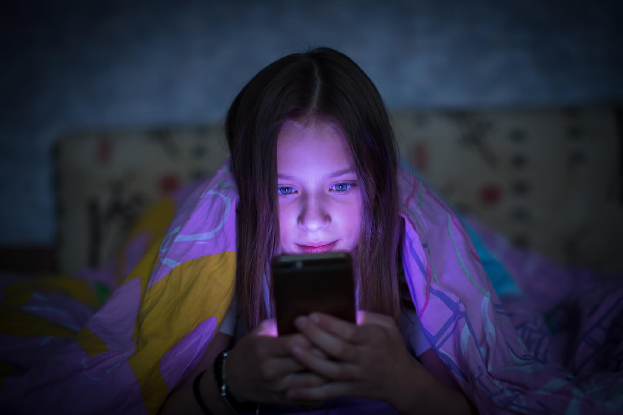 Adolescente au lit regardant un smartphone la nuit