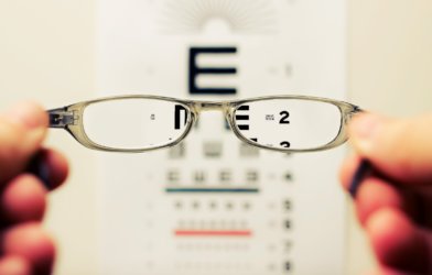 Vision test with patient holding glasses in front of chart