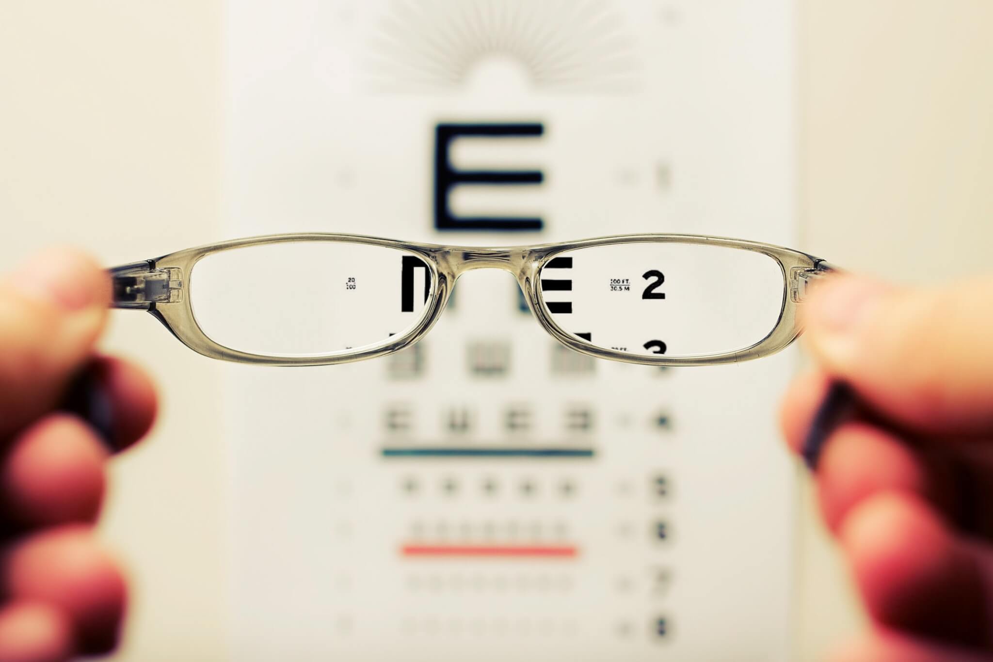 Vision test with patient holding glasses in front of chart