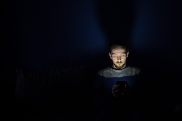 Man looking at smartphone in bed at night