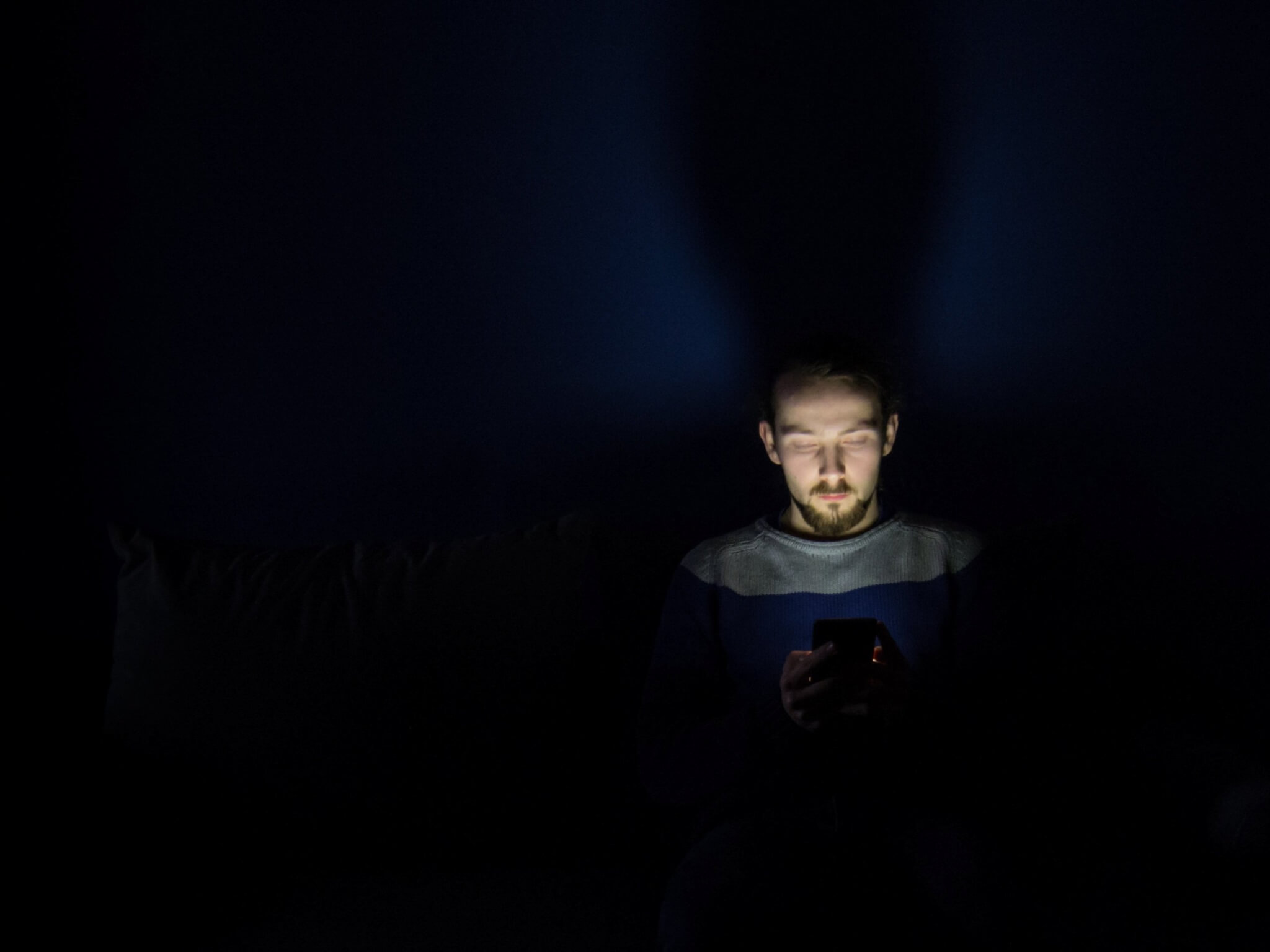 Homme regardant un smartphone au lit la nuit