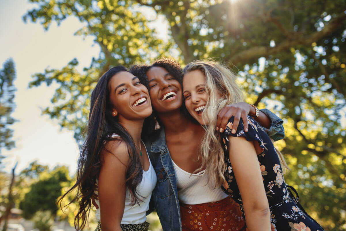 Portrait of a happy group of smiling female friends – women laughing and having fun in the park on a sunny day