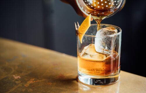 Bartender pouring an old fashioned, glass of whiskey alcohol