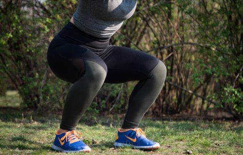 Woman exercising, doing squats, closeup of legs