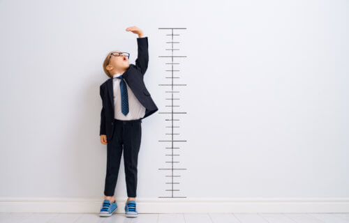 Child measuring how tall he is on height chart