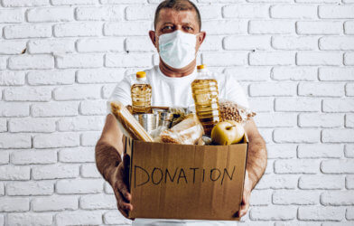 Man holding donation box of food during COVID pandemic