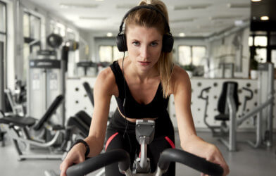 Woman working out on an exercise bike while listening to music