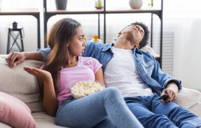 Girlfriend or wife upset with bored partner watching a movie