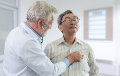 Doctor listening to middle-age patient's heartbeat