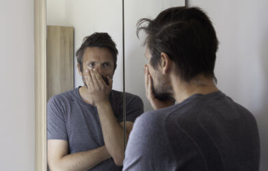 Stressed man looking in mirror