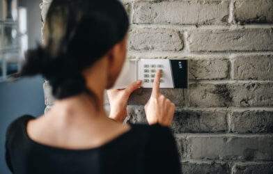 Woman turning on home alarm security system