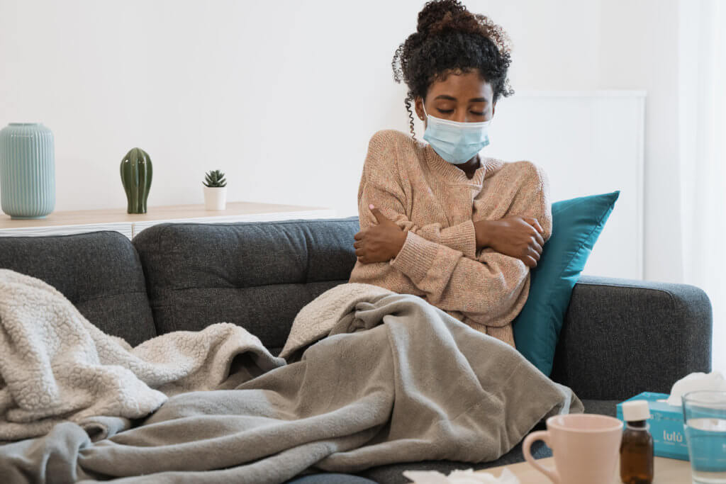 Woman feeling sick on couch with COVID or flu symptoms