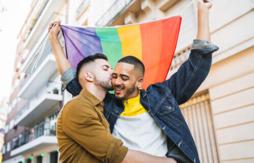 LGBTQ Pride: Gay couple embracing, holding rainbow pride