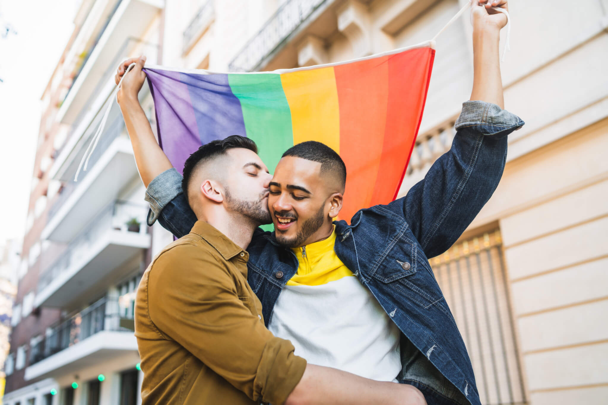 LGBTQ Pride: Gay couple embracing, holding rainbow pride
