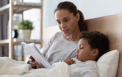 Mom reading story to child in bed