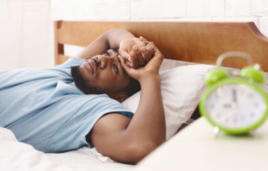 Man awake in bed, can't sleep from insomnia or sleep apnea
