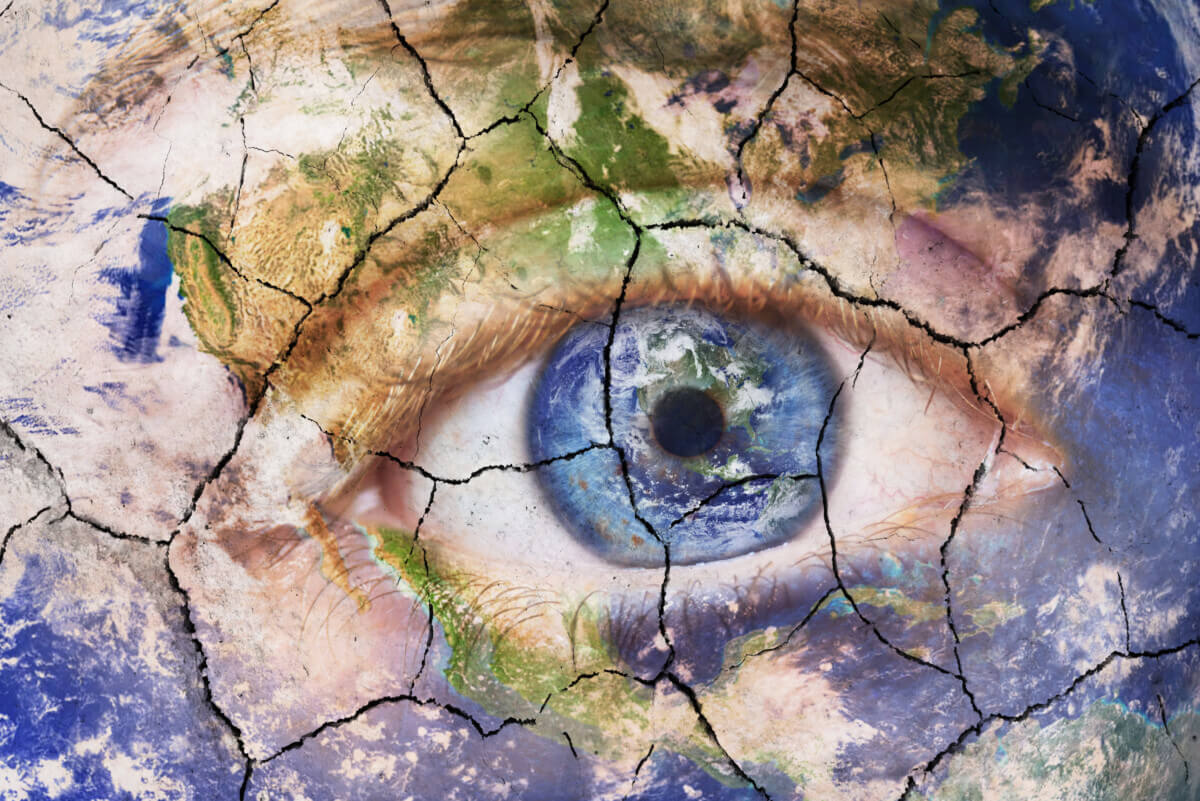 Earth extinction concept. Close up image of woman face with earth painted cracked texture with iris earth. Creative composite of macro Eye with Earth as Iris. Elements of this image furnished by NASA.