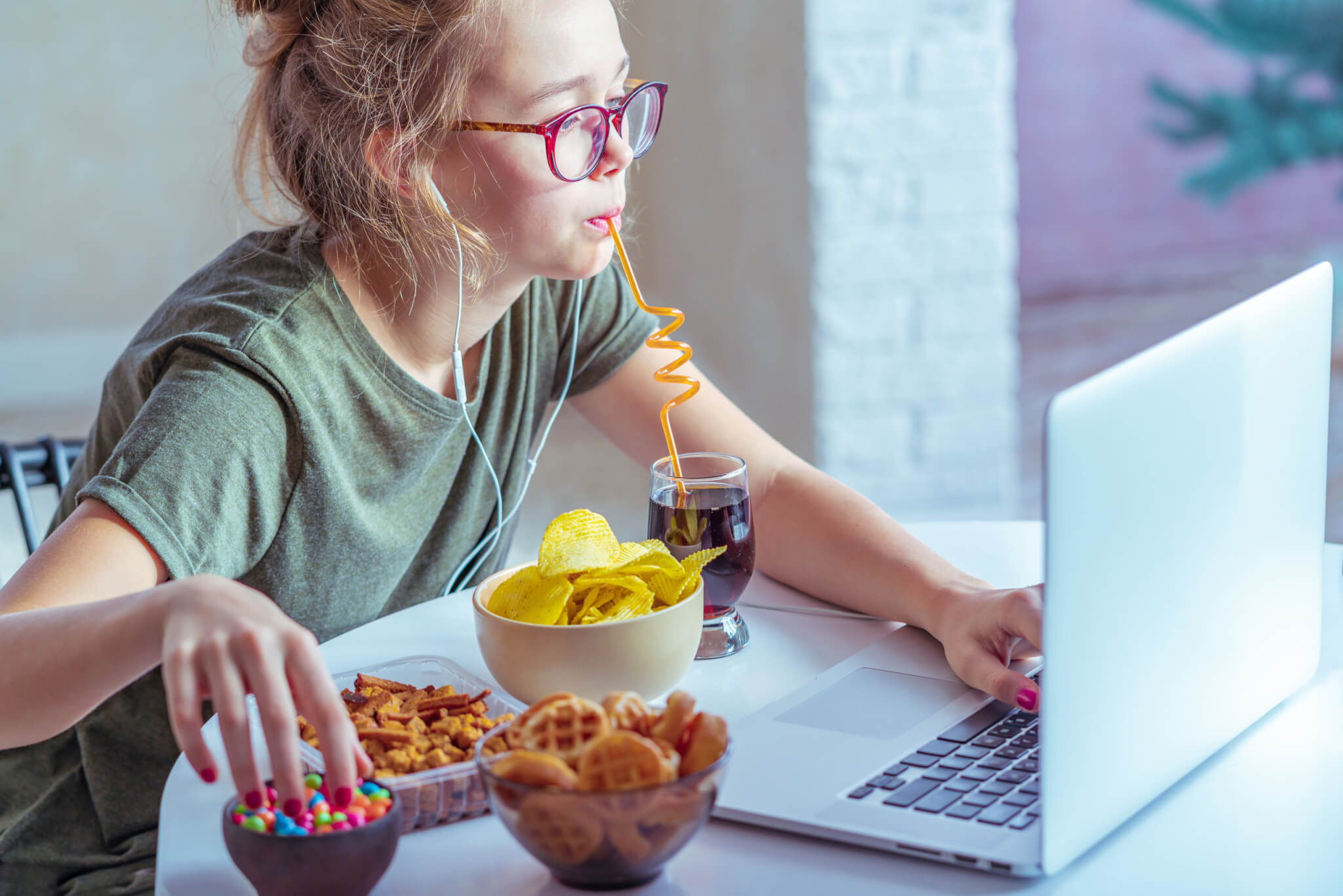 Woman eating snacks and junk food while working at desk