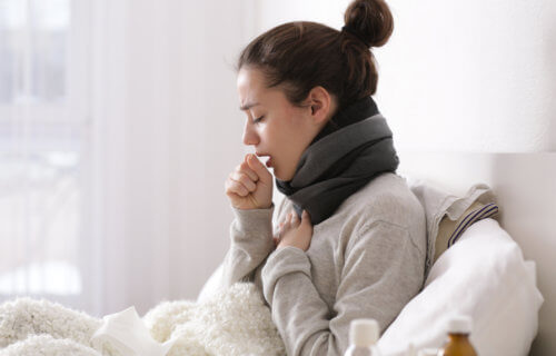Woman sick in bed with cold, cough, COVID symptoms