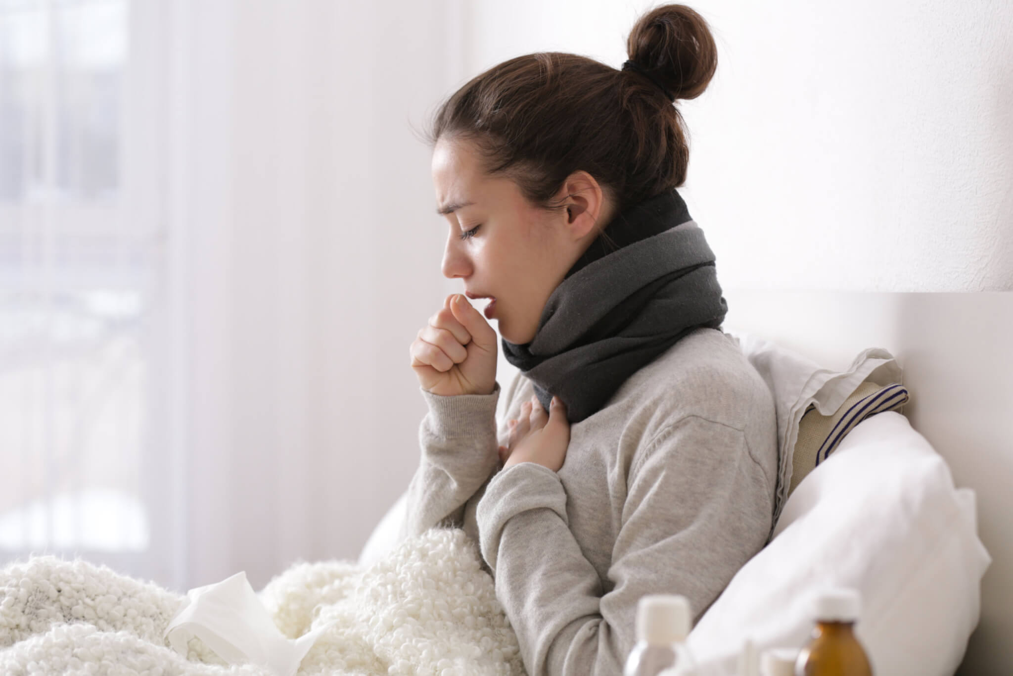 Woman sick in bed with cold, cough, COVID symptoms