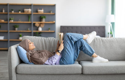 Muslim woman reading on couch