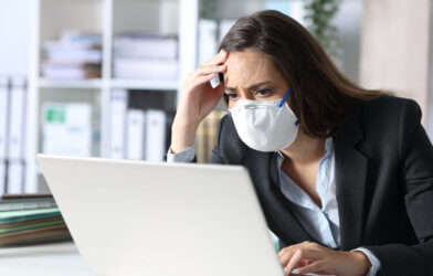 Woman in mask stressed, upset while looking at computer