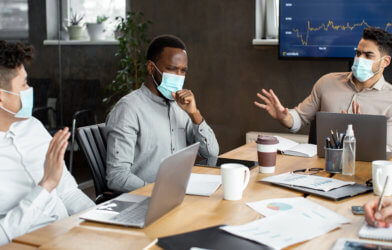 Employee with mask on coughing during work meeting