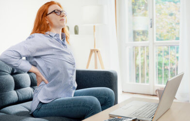 Woman dealing with back pain while working remotely from home