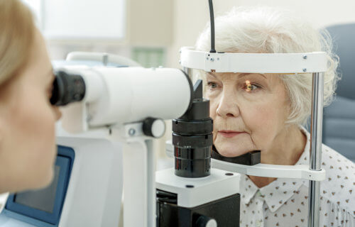 Eye doctor checking patients eyes for cataracts, vision impairment