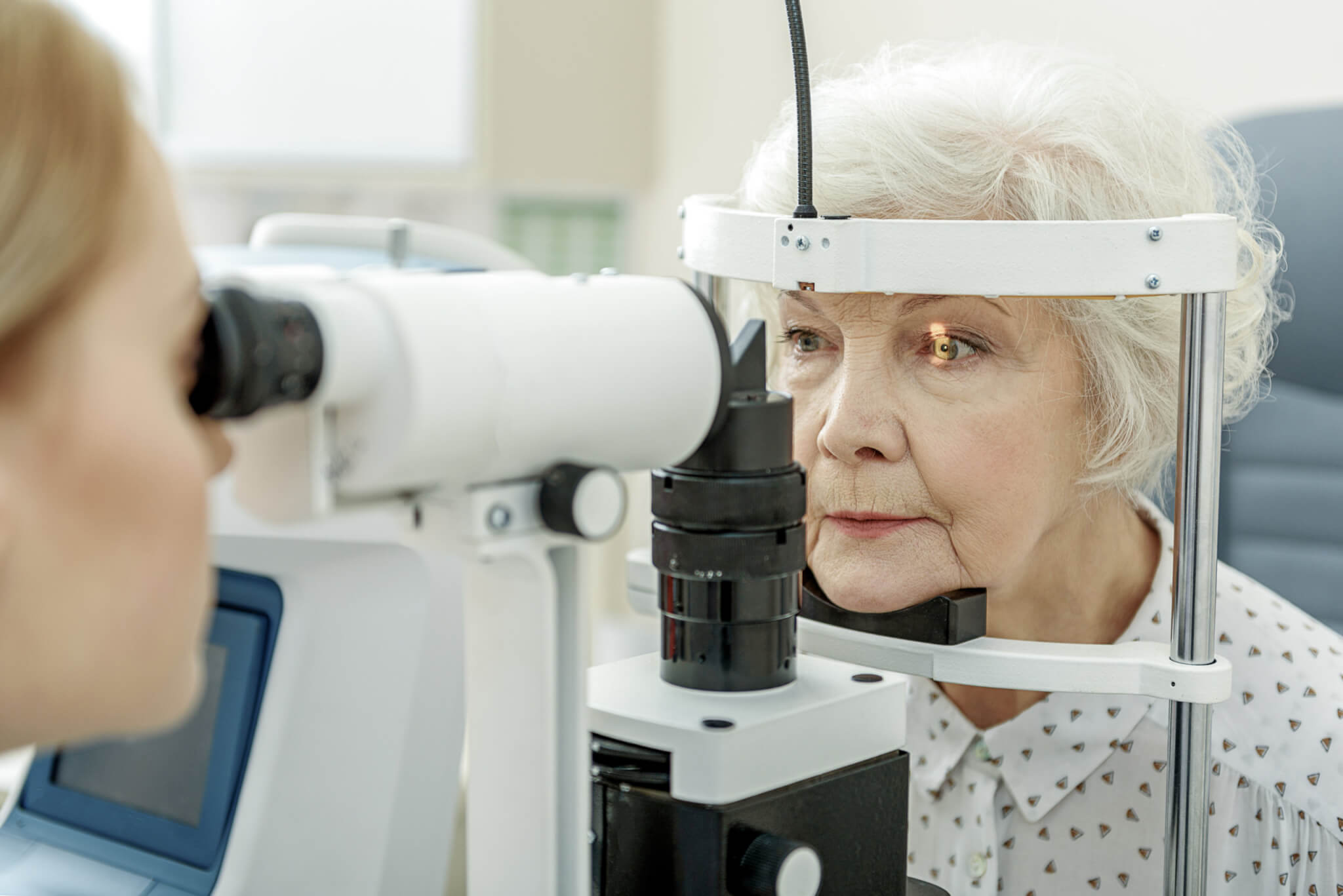 Eye doctor checking patients eyes for cataracts, vision impairment