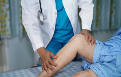 Doctor looking at patient after knee replacement surgery