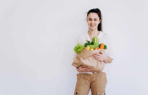 Young woman with eco-friendly paper bag filled with vegetables