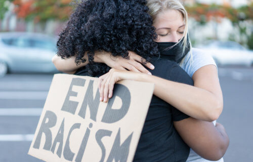 End racism: Black woman hugging a White woman at civil rights protest
