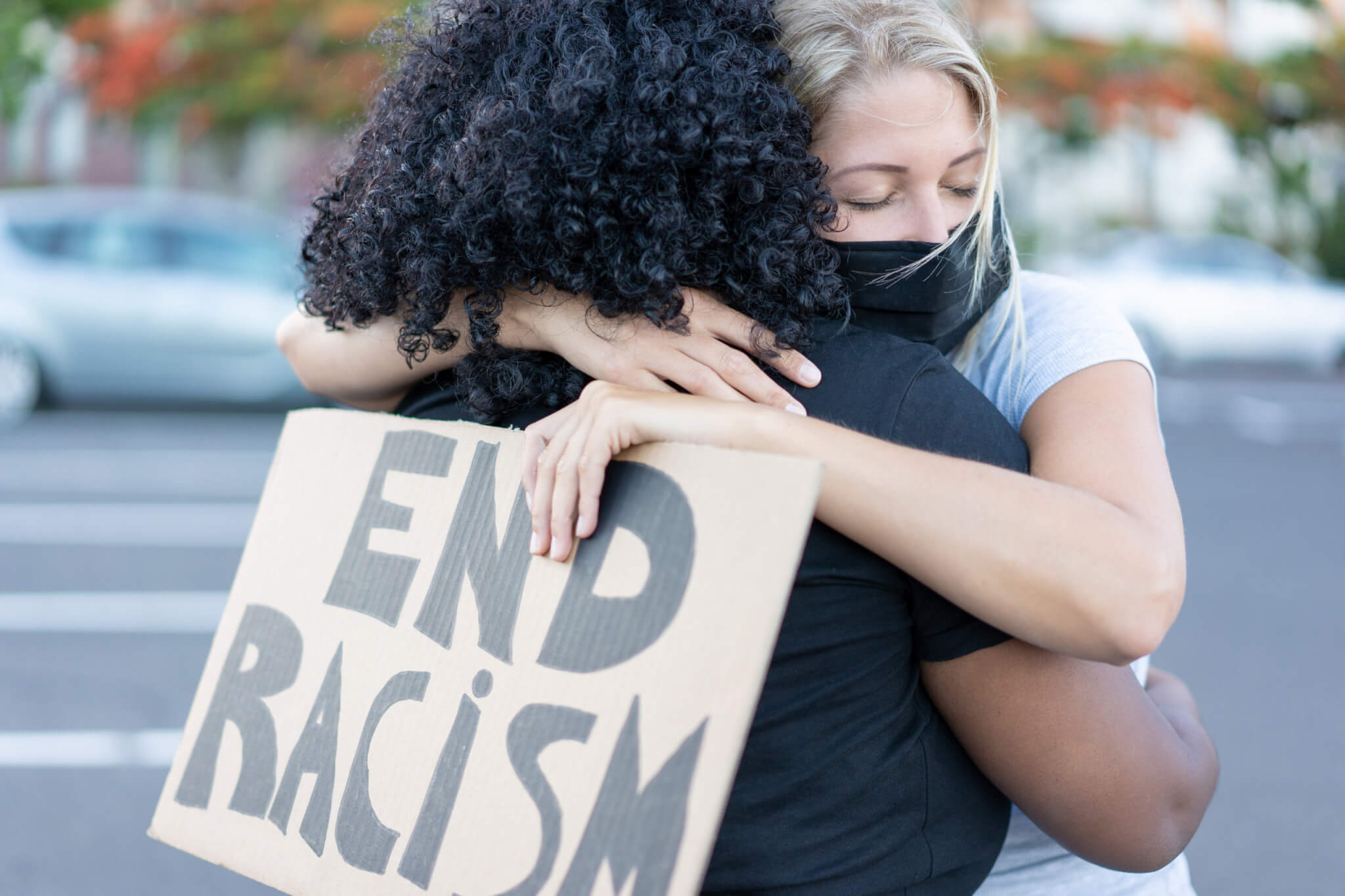 End racism: Black woman hugging a White woman at civil rights protest