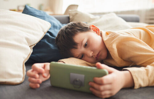 Lazy boy lying on bed watching smartphone