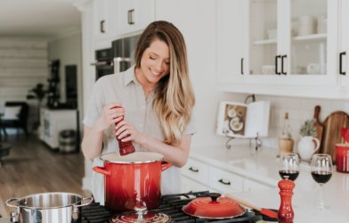 Woman adding some spice to food she's cooking on the stove