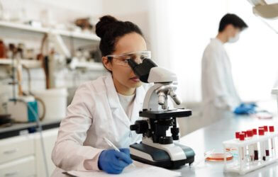 Woman looking through microscope in lab