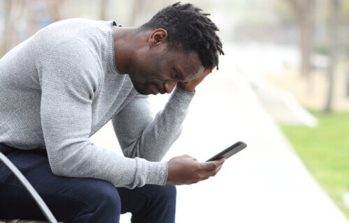 Sad, stressed man checking smartphone
