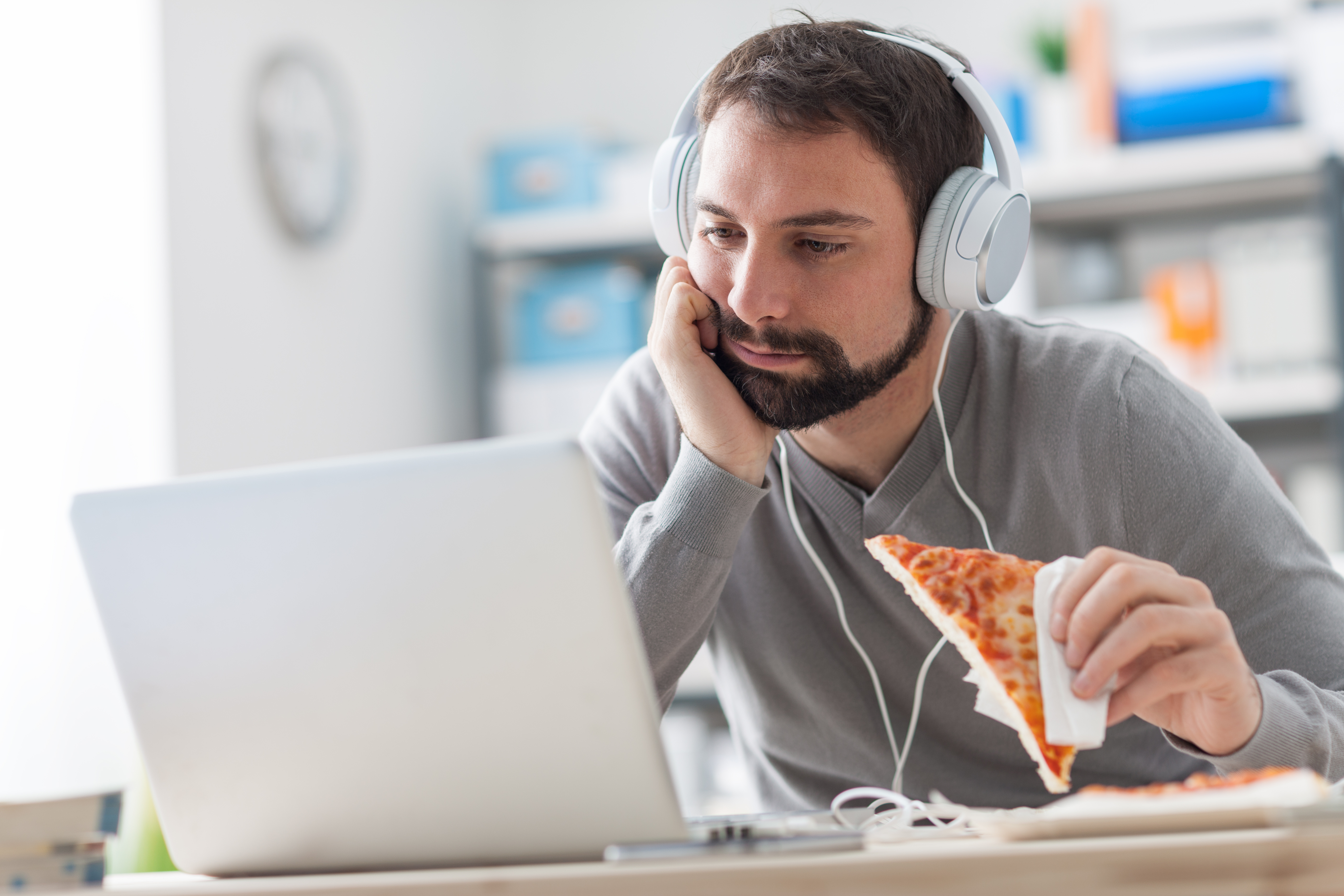 Lazy man having pizza for lunch at his work office desk