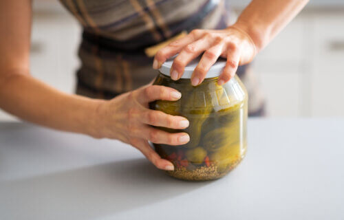 Woman struggles to open jar of pickles