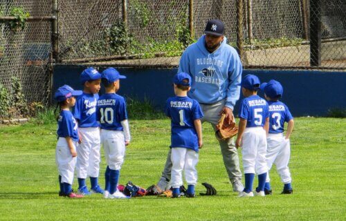 Children playing little league baseball with their coach