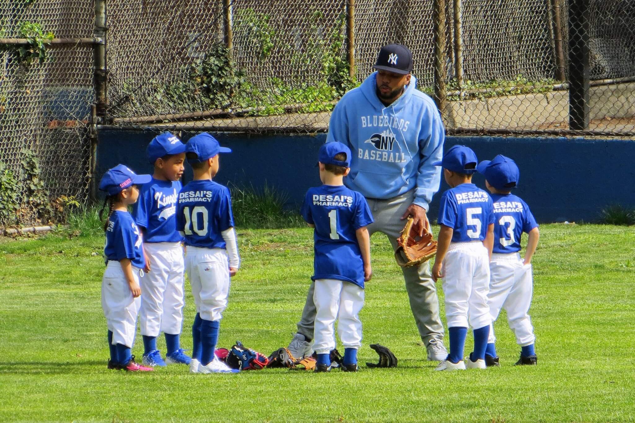 Children playing little league baseball with their coach