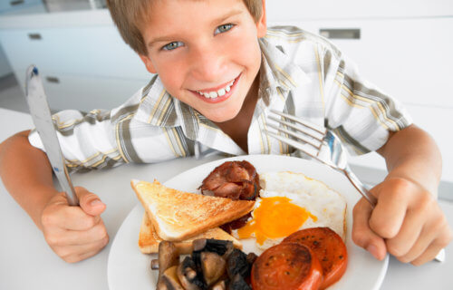 Child eating bacon and eggs for breakfast