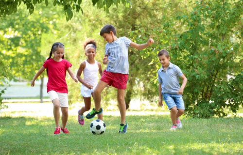 Children playing soccer outside in a park