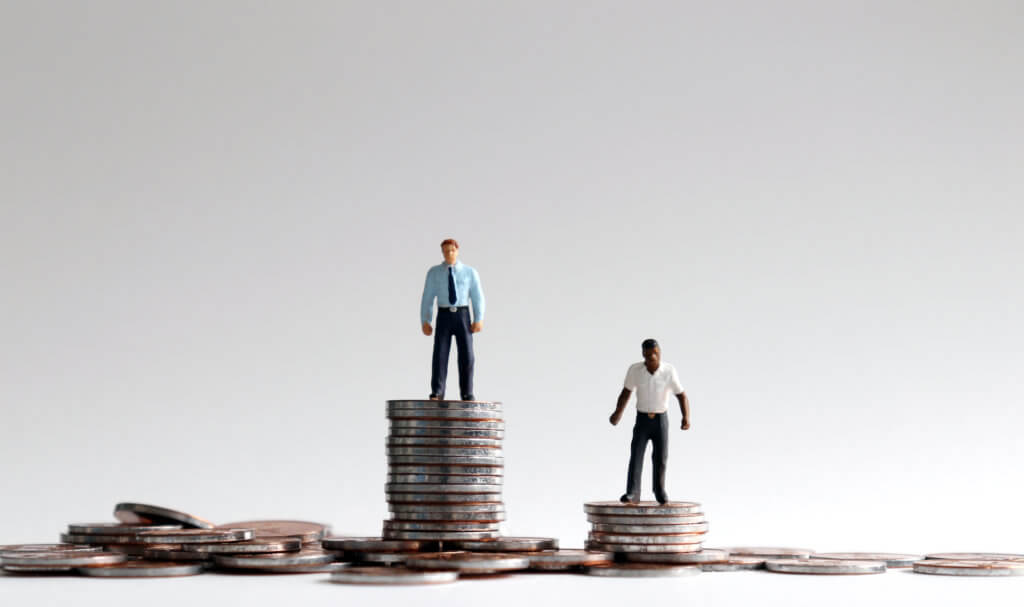 Racial wage gap concept. Miniature people standing on a pile of coins