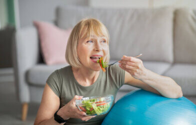 Older woman eating salad, following healthy diet and lifestyle