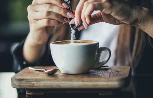 Woman putting sugar or artificial sweetener in her coffee