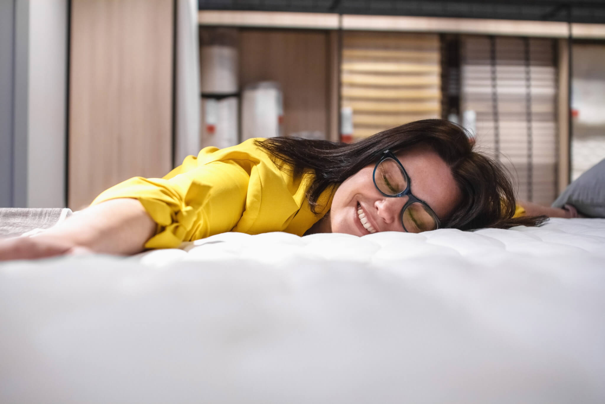 Woman testing mattress, lying on bed
